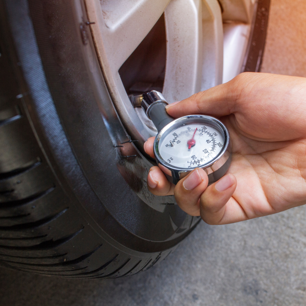 A hand is holding a tire pressure gauge.