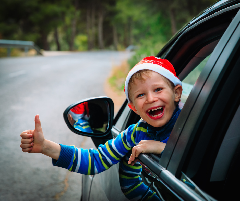A boy wearing a santa hat on a road trip.