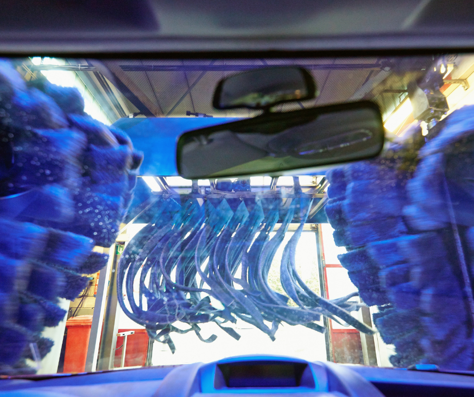 A car being washed in a blue car wash, utilizing strategies to prolong the finish.